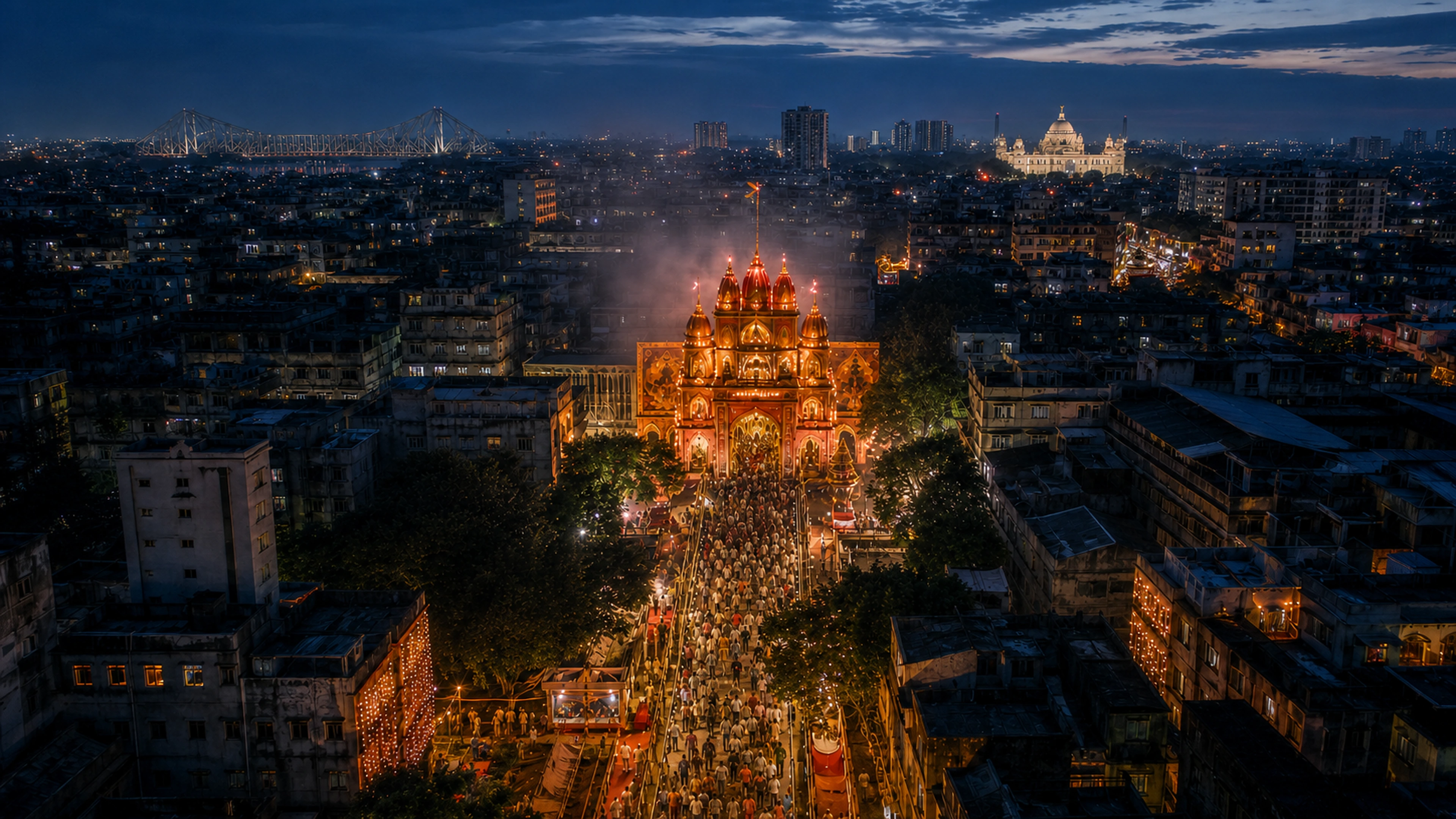 A closer aerial approach to the illuminated pandal and procession below Kolkata's landmark skyline